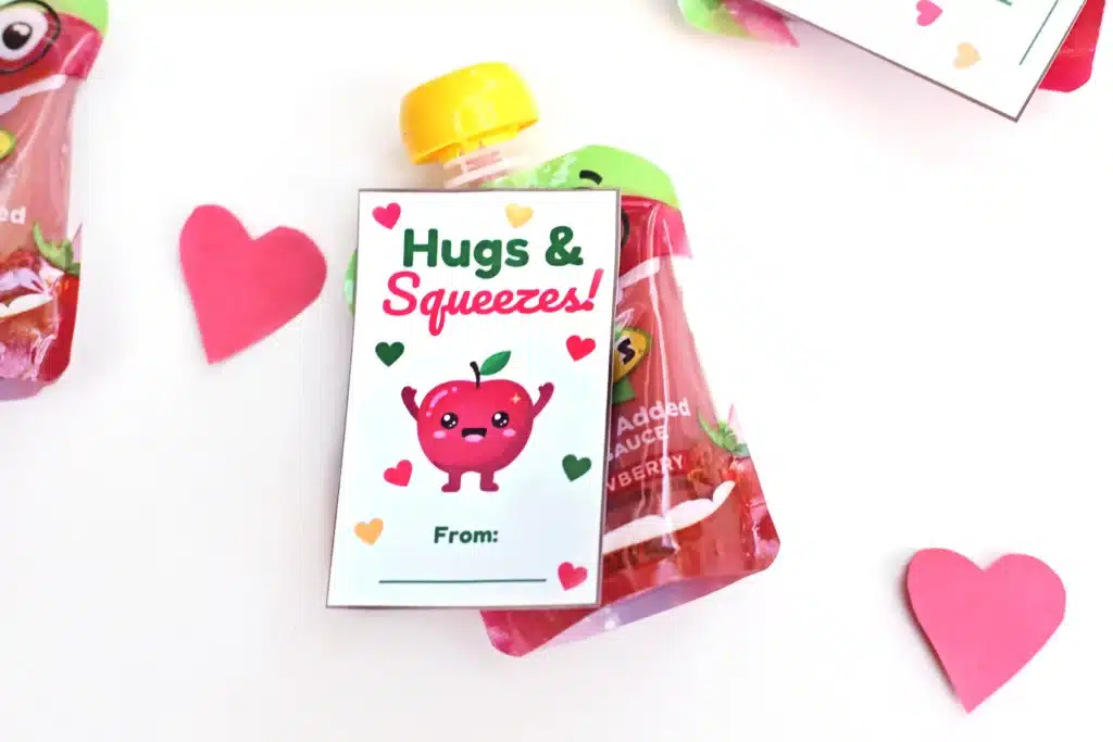 Printable Valentines: Hugs and squeezes - Cultivating Brilliant Minds printable non-candy valentines using a squeezable applesauce and a valentine that reads "hugs and kisses" and has an apple on it.