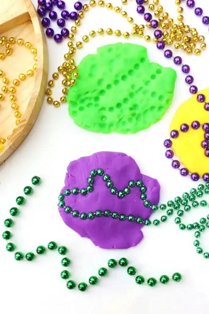 Mardi Gras Playdough Tray - Cultivating Brilliant Minds a mardi gras playdough tray using playdough, feathers, and multicolored beads