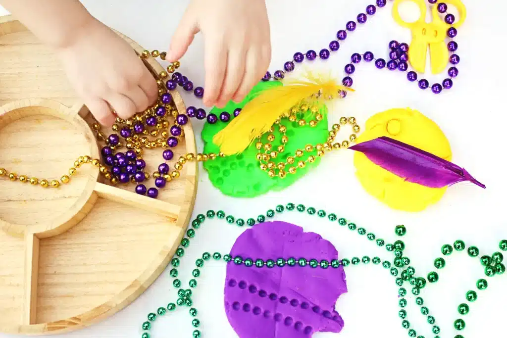 Mardi Gras Playdough Tray - Cultivating Brilliant Minds a mardi gras playdough tray using playdough, feathers, and multicolored beads