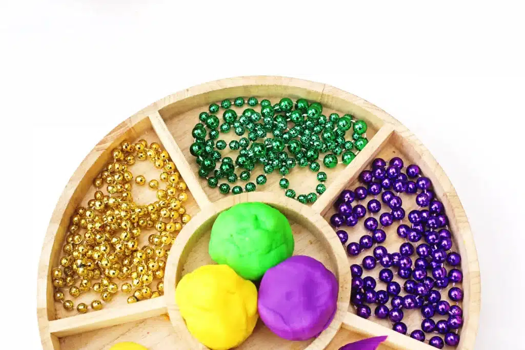 Mardi Gras Playdough Tray - Cultivating Brilliant Minds a mardi gras playdough tray using playdough, feathers, and multicolored beads