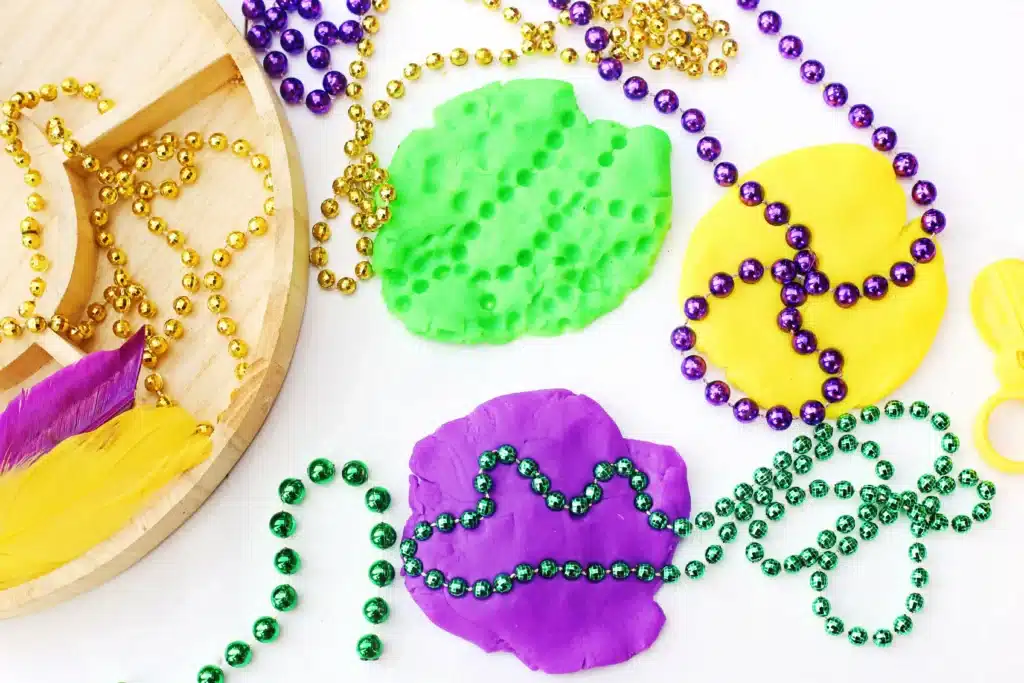 Mardi Gras Playdough Tray - Cultivating Brilliant Minds colored beaded necklaces pressed into playdough