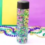Mardi Gras Sensory Bottle - Cultivating Brilliant Minds a mardi gras sensory bottle that uses mardi gras beads and glitter in water