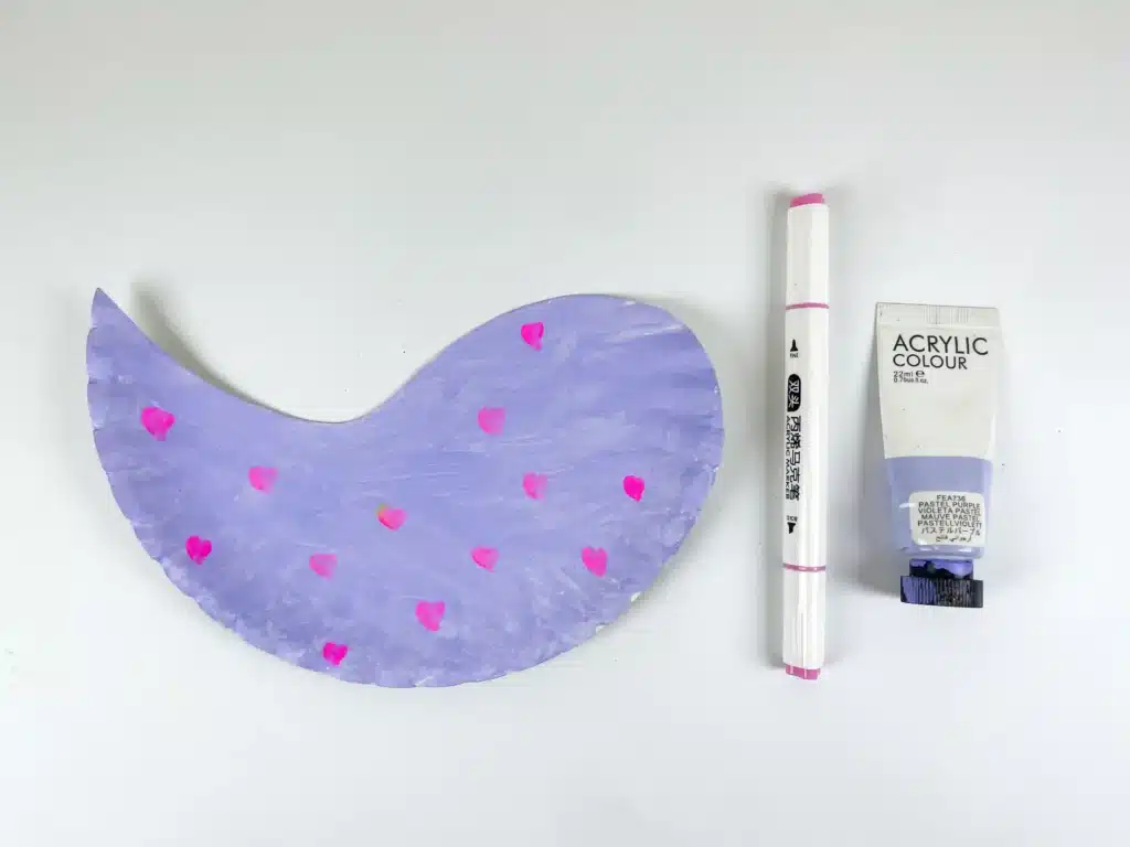Lovebird Paper Plate Craft for Valentine's Day - Cultivating Brilliant Minds a paper plate cut into the shape of a bird painted purple with pink hearts