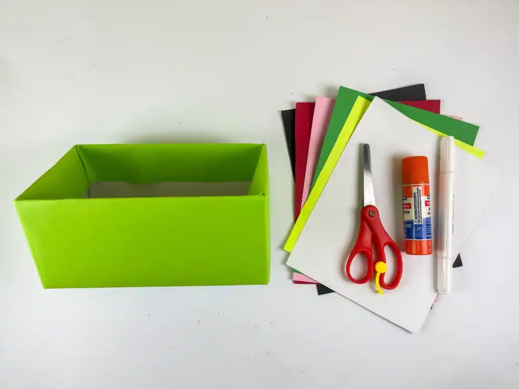 Frog Valentine Box - Cultivating Brilliant Minds a valentine box covered in green paper, colored construction paper, scissors, and glue