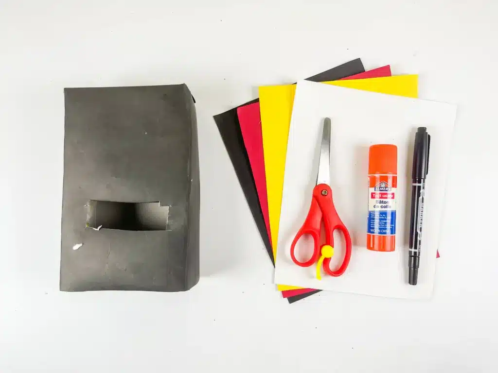 Penguin Valentine Box - Cultivating Brilliant Minds box covered in black paper, colored construction paper, scissors, glue, and a black marker