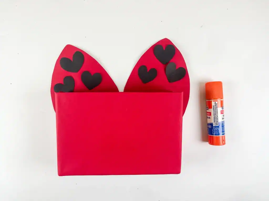 DIY Ladybug Valentine Box - Cultivating Brilliant Minds a box covered in red paper with red construction paper wings that have black hearts on them for spots