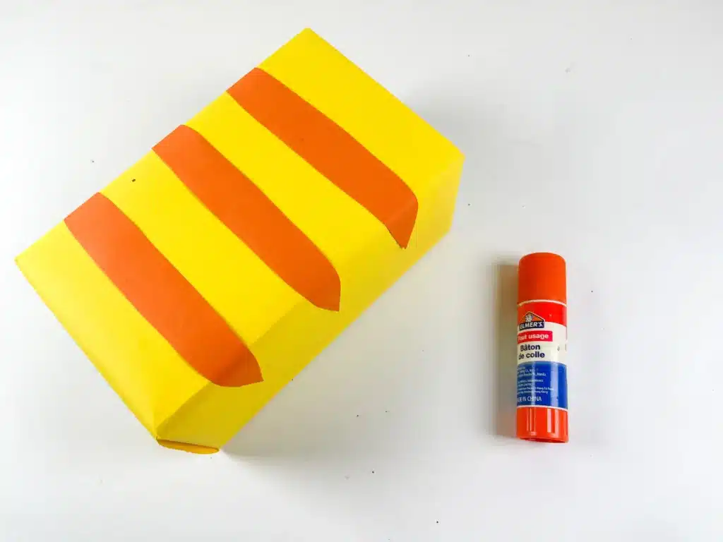 Cat Valentine Box - Cultivating Brilliant Minds a box covered with yellow construction paper and with strips of orange construction paper on top for stripes