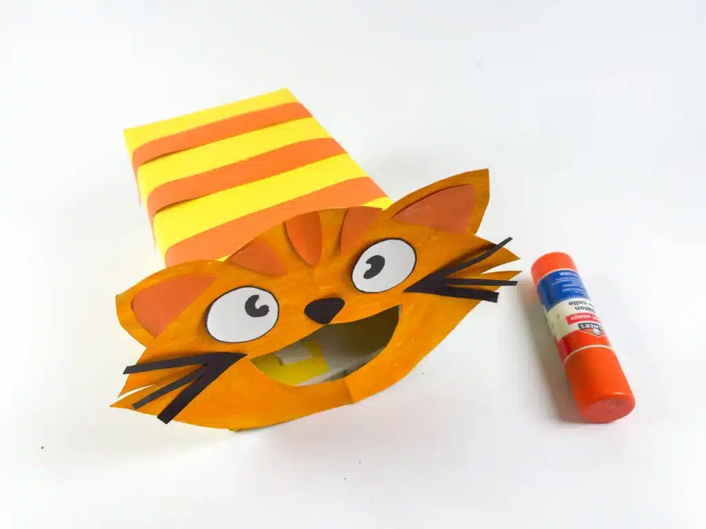 Cat Valentine Box - Cultivating Brilliant Minds a cat valentine box that has a box covered in yellow and orange construction paper to be stripes with a cat face made out of construction paper attached to the front with a hole for the cat's mouth for valentines