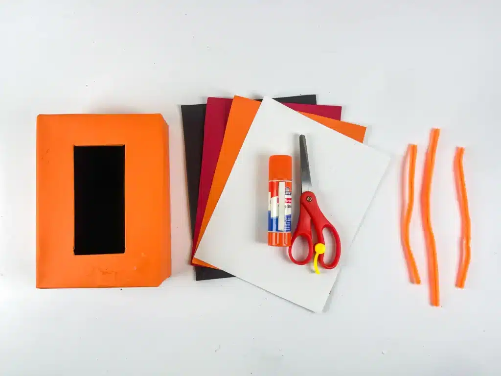Monster Valentine Box - Cultivating Brilliant Minds a box covered in orange paper, colored construction paper, glue, scissors, and orange pipe cleaners