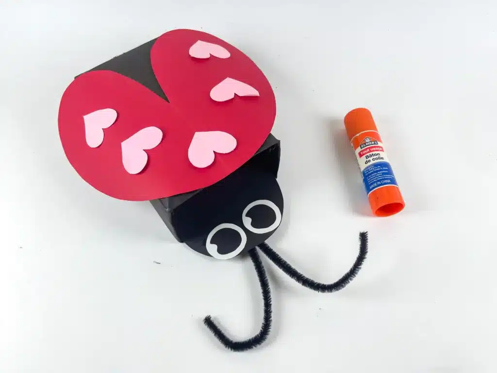 Ladybug Valentines Box - Cultivating Brilliant Minds a ladybug valentines box that has a box covered in black paper with a construction paper ladybug head and construction paper wings with hearts