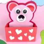 Love Bear Valentine Box - Cultivating Brilliant Minds love bear valentine box: a box covered in red paper with white hearts and a construction paper bear taped inside sticking out of the box