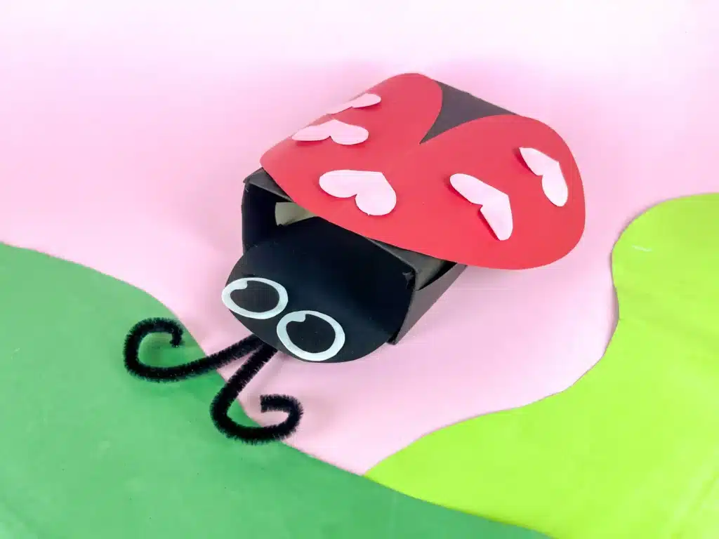 Ladybug Valentines Box - Cultivating Brilliant Minds a ladybug valentines box that has a box covered in black paper with a construction paper ladybug head and construction paper wings with hearts