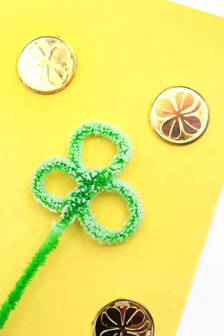 Salt Crystal Shamrock Science Experiment - a green pipe cleaner shaped into a clover with salt stuck on it