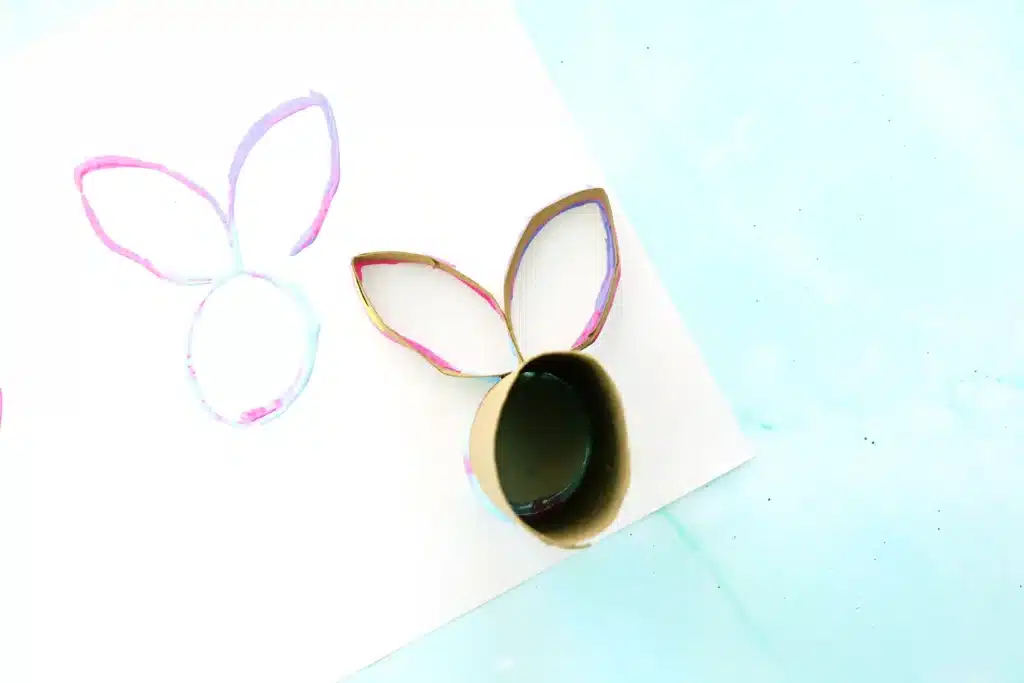 Bunny Stamp Art with Toilet Paper Rolls - Cultivating Brilliant Minds a toilet paper roll with two small sections cut off, shaped into bunny ears, and glued onto the toilet paper roll with paint on it stamped down on paper