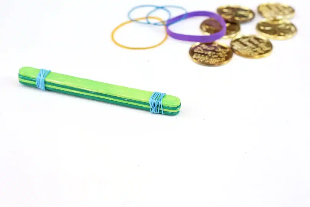 St. Patrick's Day Gold Coin Catapults - Cultivating Brilliant Minds popsicle sticks with rubber bands around them