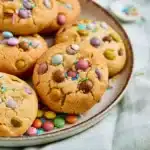 Chewy Easter Cookies - Cultivating Brilliant Minds chewy cookies with easter colored pastel m&ms on a white plate on top of a light green plaid tea towel