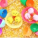 Chick Hatch Sensory Bin - Cultivating Brilliant Minds a chick hatch sensory bin with corn kernels, easter eggs, and chicks