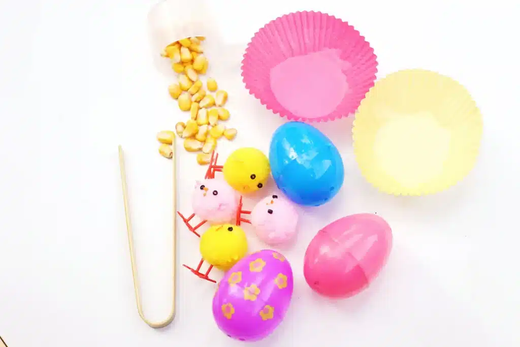 Chick Hatch Sensory Bin - Cultivating Brilliant Minds cupcake liners, corn kernels, chicks, easter eggs and tongs