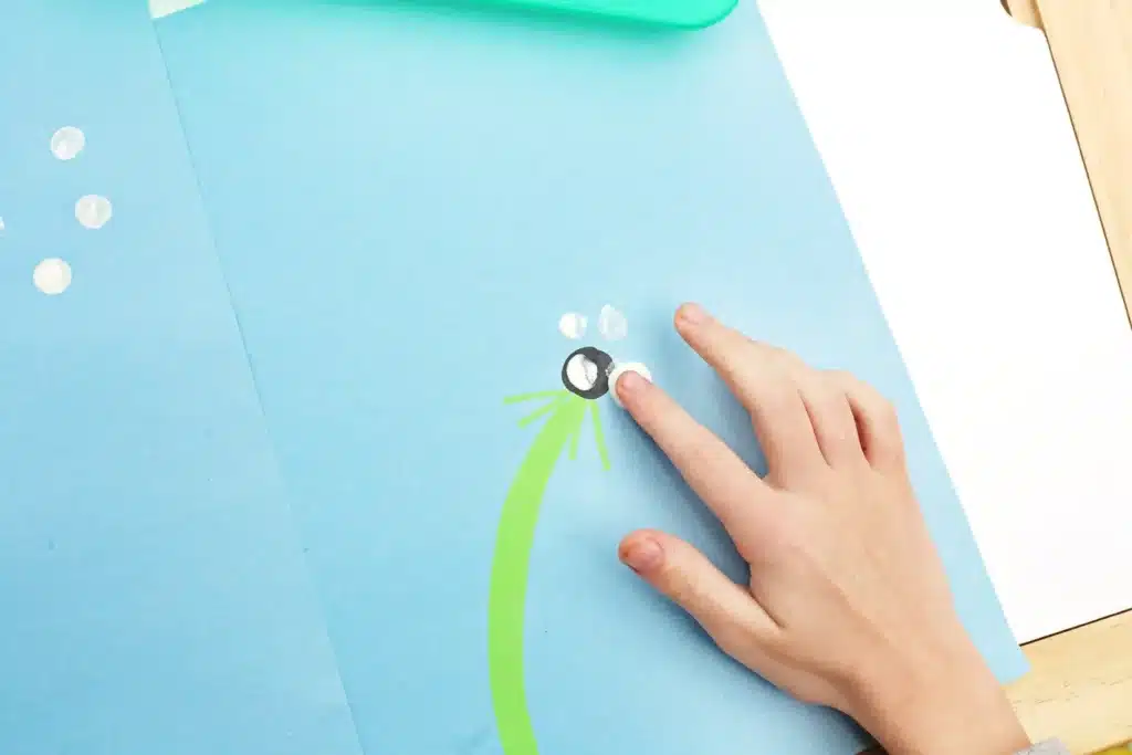 Fingerprint Dandelions - Cultivating Brilliant Minds a child stamping his finger with white paint on it to create a dandelion