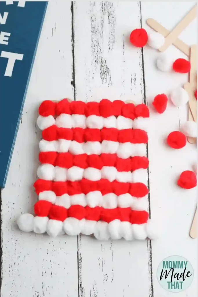 Dr Seuss Crafts for Kids - Cultivating Brilliant Minds a cat in the hat craft that uses red and white pom poms to create the cat in the hat's striped hat