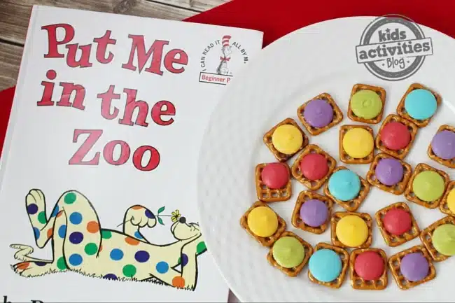 Dr. Seuss Inspired Treats - Cultivating Brilliant Minds pretzels with colroed candy melts on top next to the book "Put me in the zoo"
