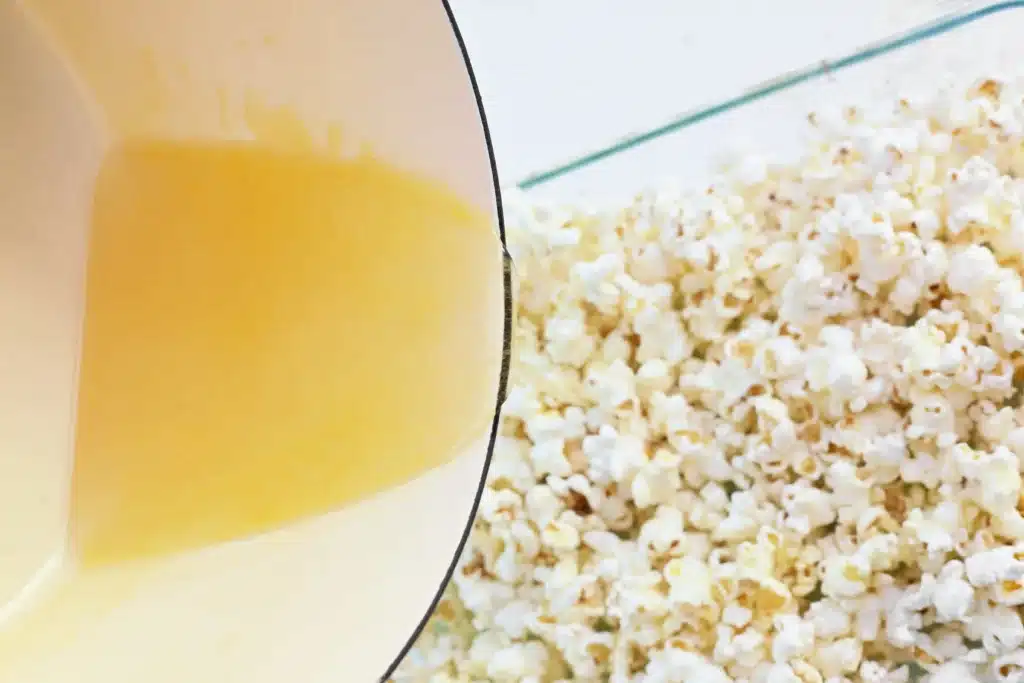 Sheep Popcorn Balls - Cultivating Brilliant Minds a pan dumping the sugar, water, corn syrup mixture over the popcorn