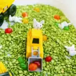Easter Construction Sensory Bin - Cultivating Brilliant Minds an easter construction sensory bin made of split peas, jelly beans, toy bunnies, and construction vehicles