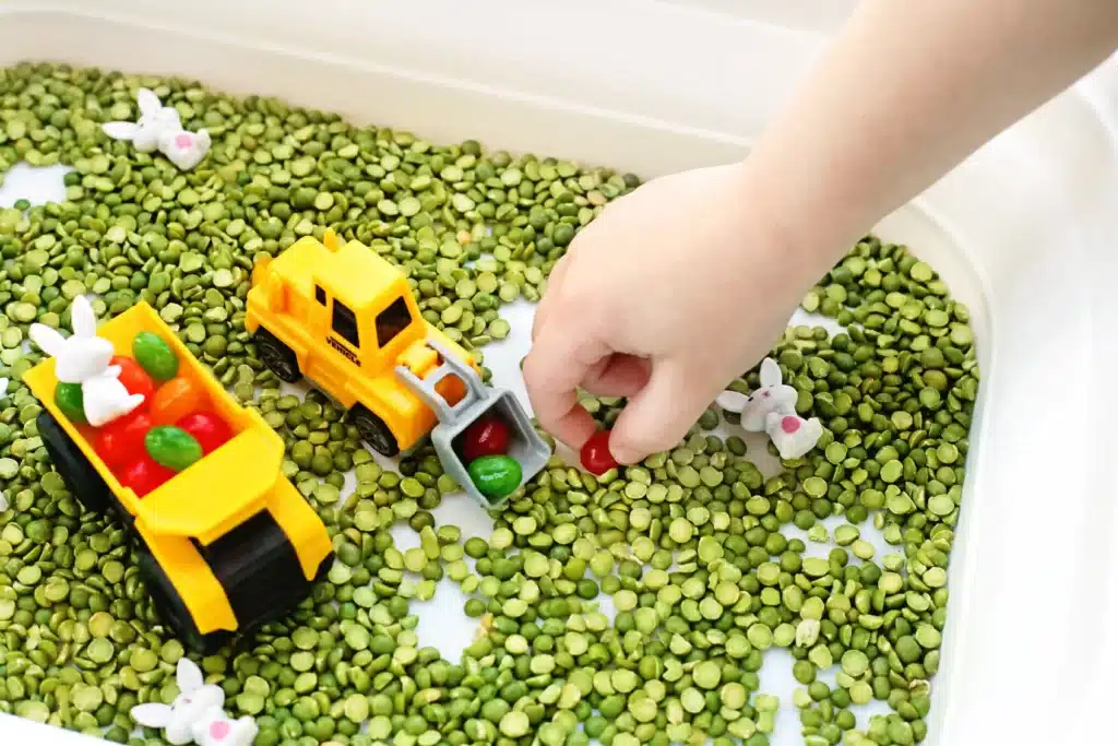 Easter Construction Sensory Bin - Cultivating Brilliant Minds a kid picking up a jelly bean