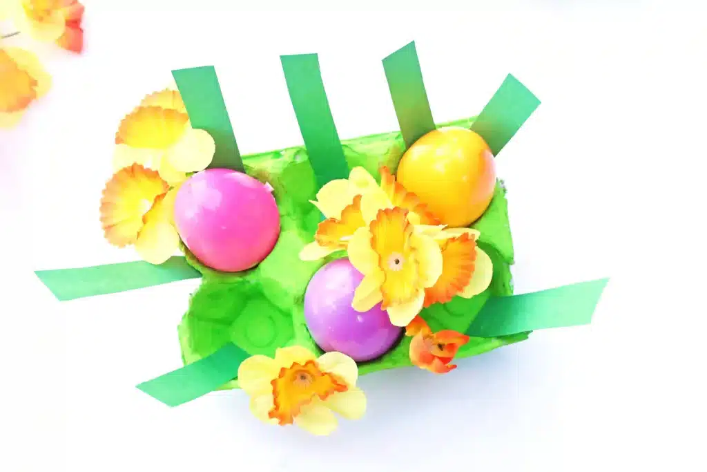 Easter Egg Garden Craft - Cultivating Brilliant Minds an easter egg garden craft that has an egg carton painted green with plastic easter eggs, flowers, and strips of green paper for grass