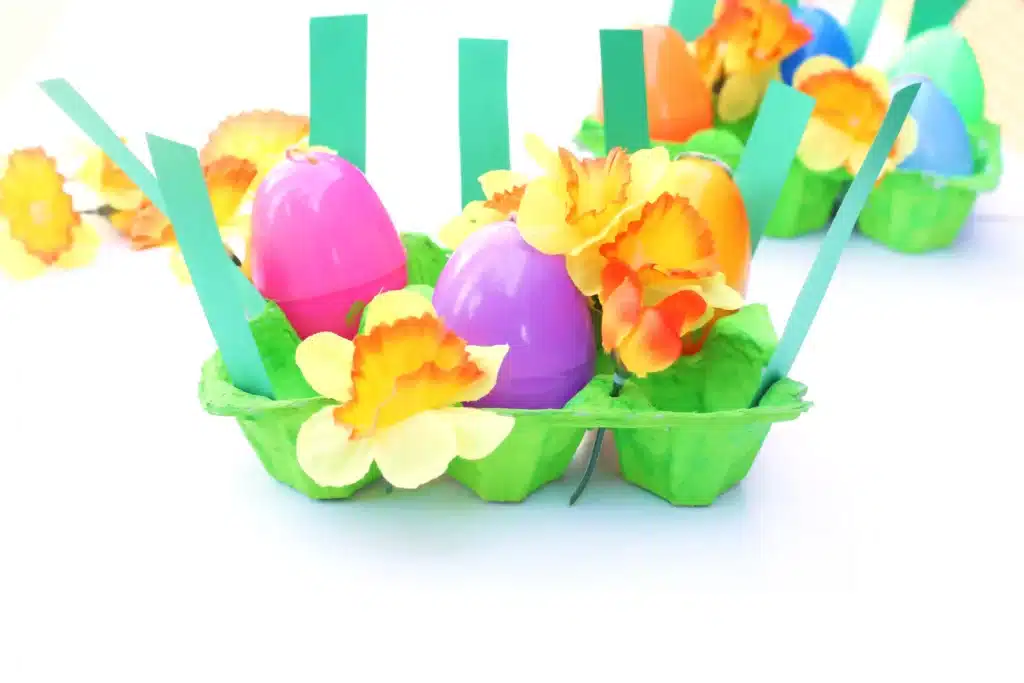 Easter Egg Garden Craft - Cultivating Brilliant Minds an easter egg garden craft that has an egg carton painted green with plastic easter eggs, flowers, and strips of green paper for grass