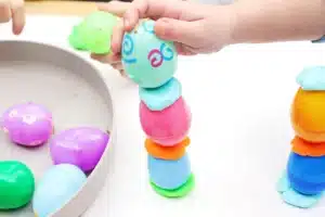 a kid stacking an easter egg tower with playdough in between each egg