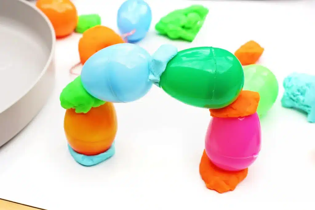Easter Egg Tower STEM Project - Cultivating Brilliant Minds easter eggs stacked into a rainbow shape with playdough holding the eggs together