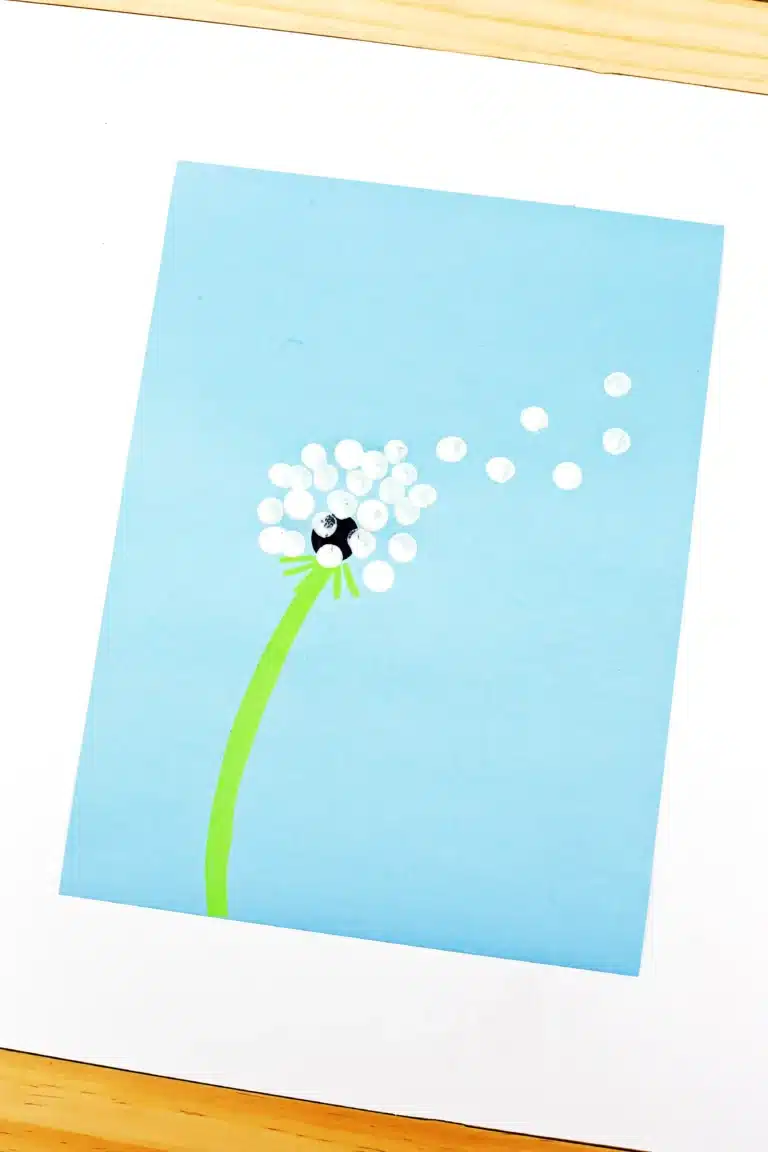 a dandelion painted on a blue piece of paper with fingerprints for the flower
