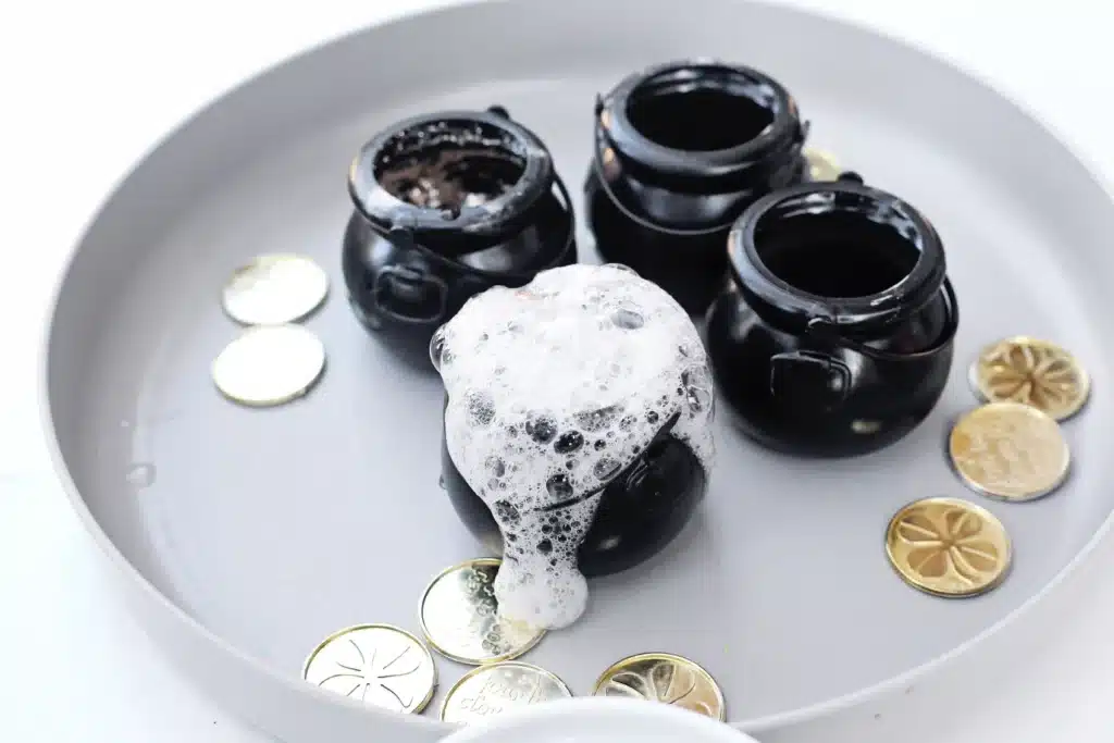 Fizzy Pot of Gold Experiment - Cultivating Brilliant Minds a black cauldron overflowing with vinegar and baking soda