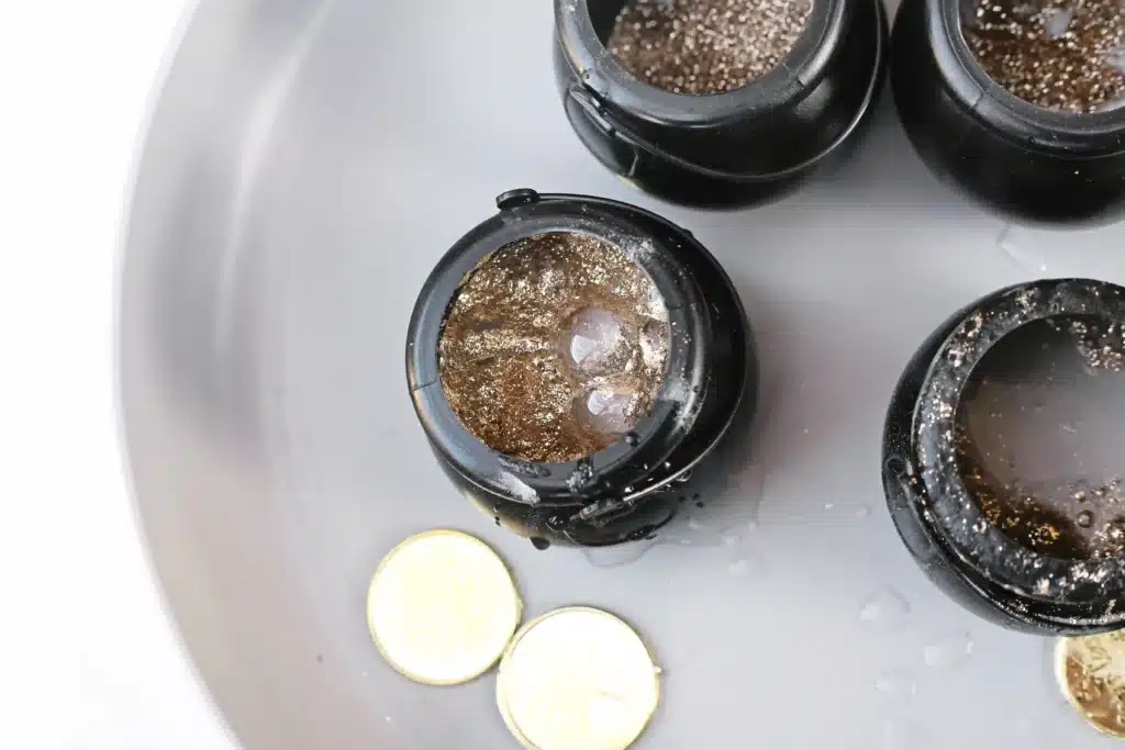 Fizzy Pot of Gold Experiment - Cultivating Brilliant Minds fizzy pot of gold experiment that uses cauldron pots, gold glitter, baking soda, and vinegar to create a "volcano"