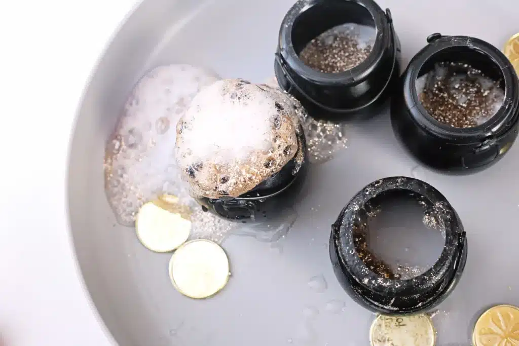 Fizzy Pot of Gold Experiment - Cultivating Brilliant Minds fizzy pot of gold experiment that uses cauldron pots, gold glitter, baking soda, and vinegar to create a "volcano"