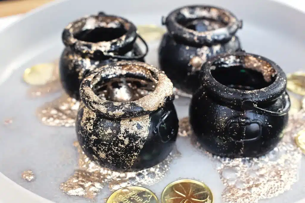 Fizzy Pot of Gold Experiment - Cultivating Brilliant Minds fizzy pot of gold experiment that uses cauldron pots, gold glitter, baking soda, and vinegar to create a "volcano"