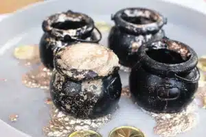 fizzy pot of gold experiment that uses cauldron pots, gold glitter, baking soda, and vinegar