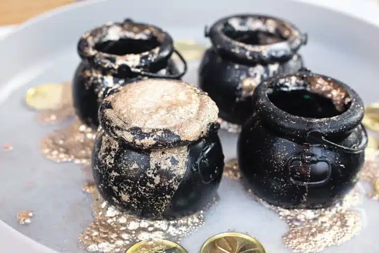 fizzy pot of gold experiment that uses cauldron pots, gold glitter, baking soda, and vinegar