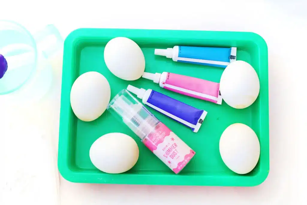 Galaxy Easter Eggs - Cultivating Brilliant Minds hard boiled eggs, purple, pink, and blue food coloring, a tray, and edible glitter