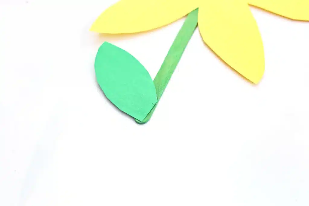 Cupcake Liner Daffodil - Cultivating Brilliant Minds a leaf cut out of green construction paper glued to a green popsicle stick