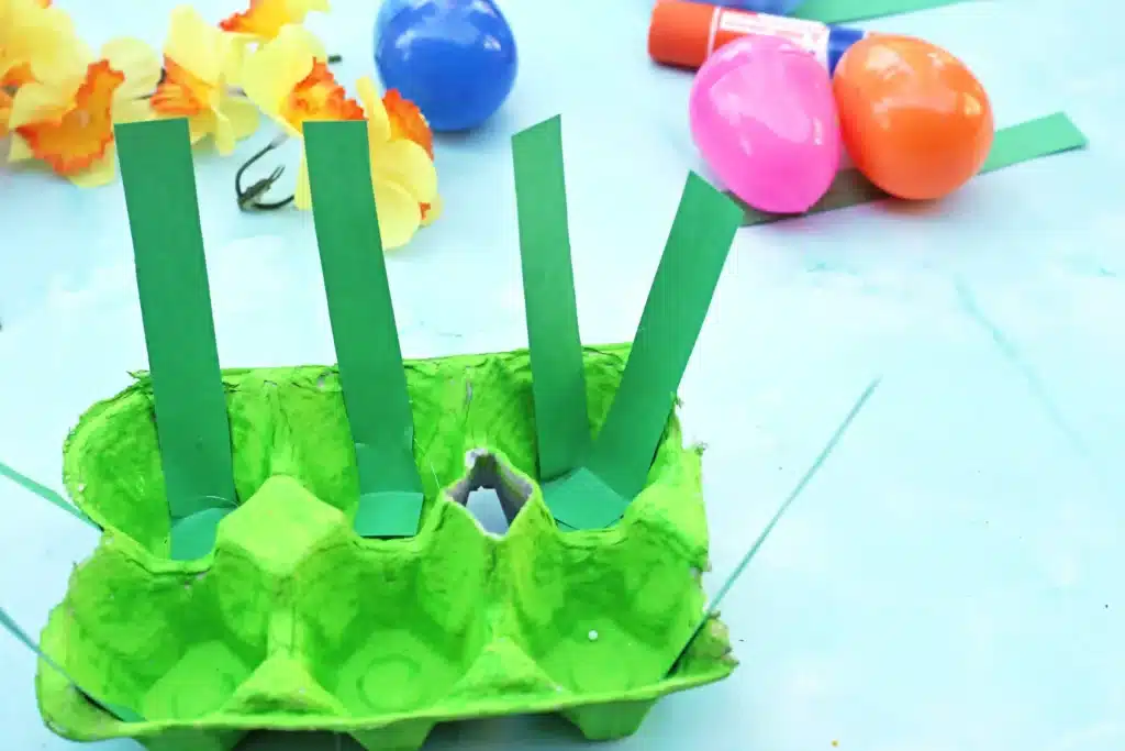 Easter Egg Garden Craft - Cultivating Brilliant Minds green strips of paper glued into the egg carton painted green