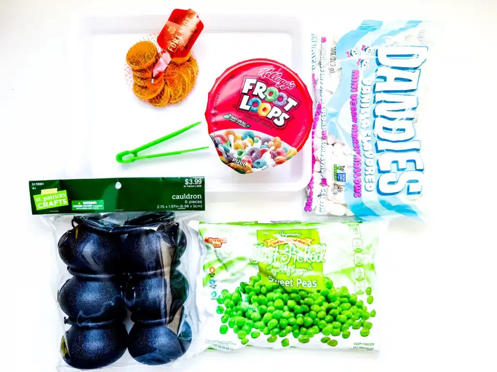 Edible St. Patrick's Day Sensory Bin - Cultivating Brilliant Minds cauldrons, froot loops, frozen peas, chocolate coins, and mini marshmallows