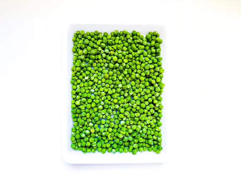 Edible St. Patrick's Day Sensory Bin - Cultivating Brilliant Minds frozen peas in a tray
