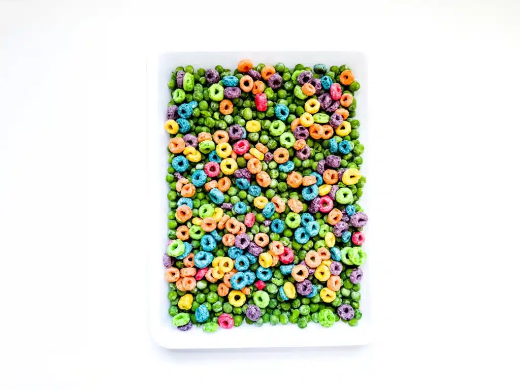 Edible St. Patrick's Day Sensory Bin - Cultivating Brilliant Minds frozen peas and froot loops on a tray