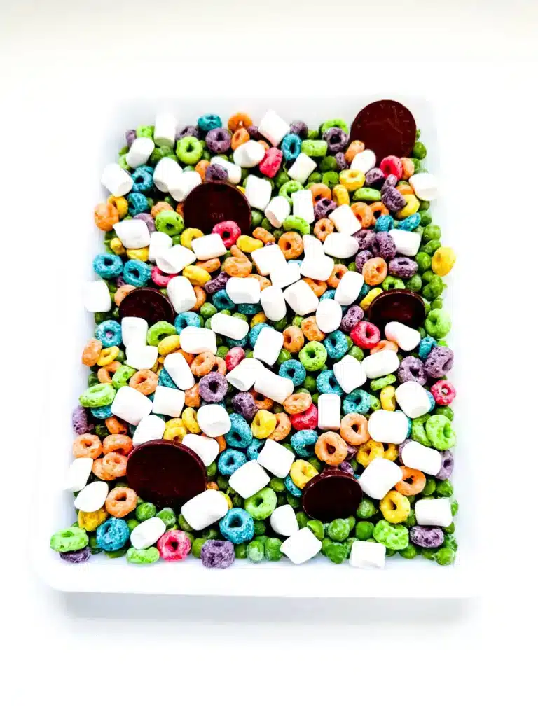 Edible St. Patrick's Day Sensory Bin - Cultivating Brilliant Minds a st. patrick's day sensory bin that has green peas, froot loops, marshmallows, and chocolate coins.