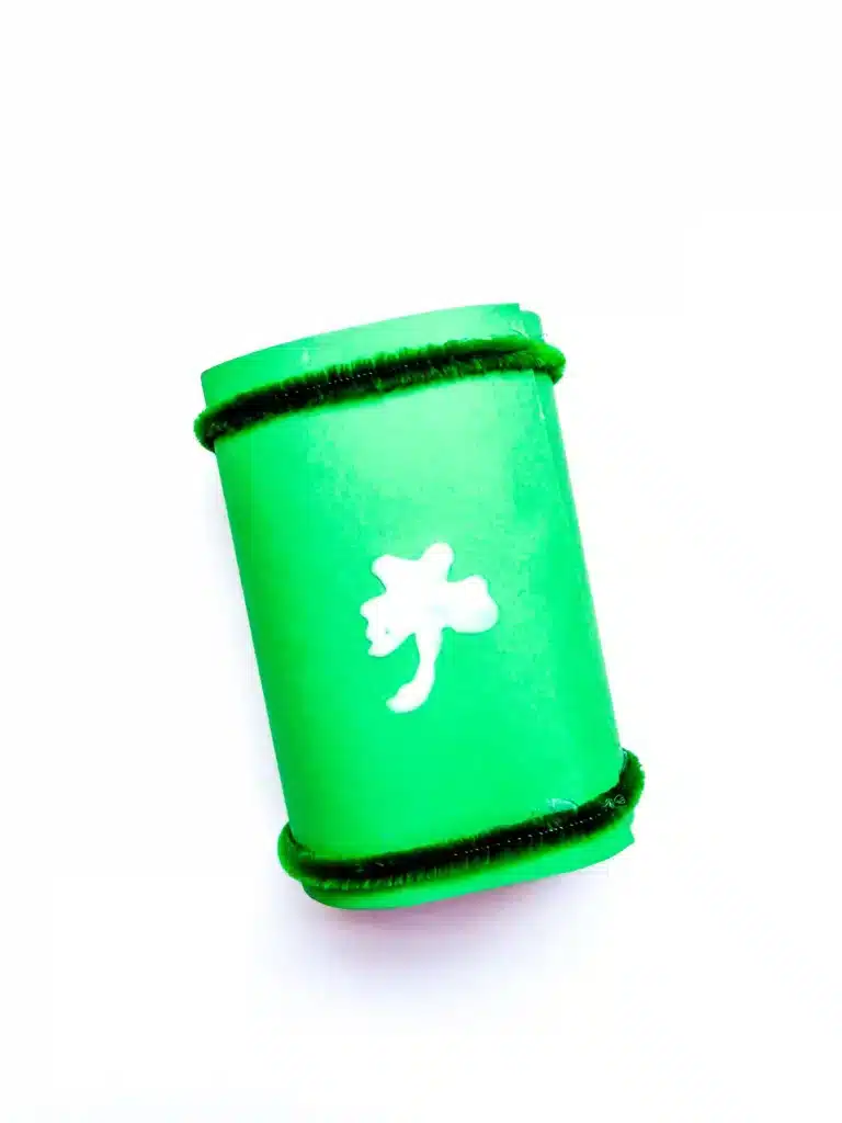 Leprechaun Lookers for St. Patrick's Day - Cultivating Brilliant Minds a shamrock of glue drawn on top of two toilet paper rolls covered with green paper and green pipe cleaners glued on the ends