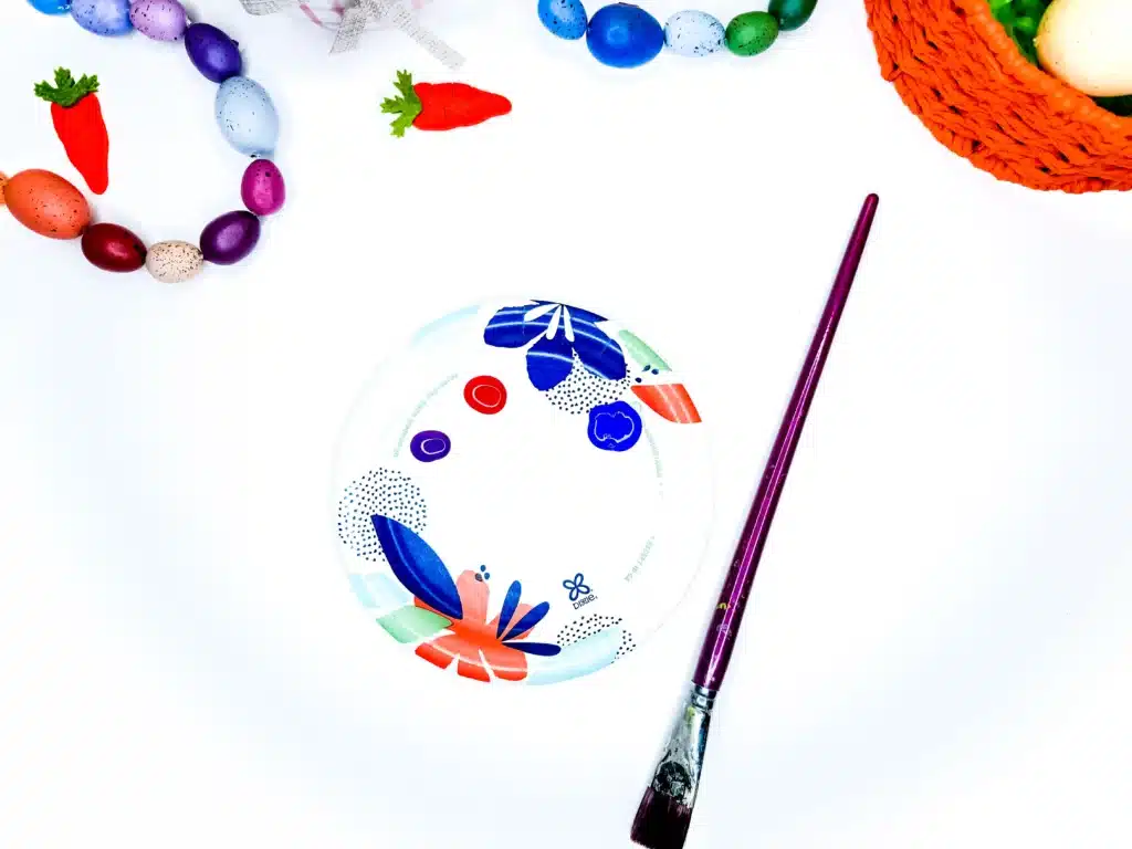 Bunny Handprint Craft For Easter - Cultivating Brilliant Minds paint on a paper plate next to a paintbrush