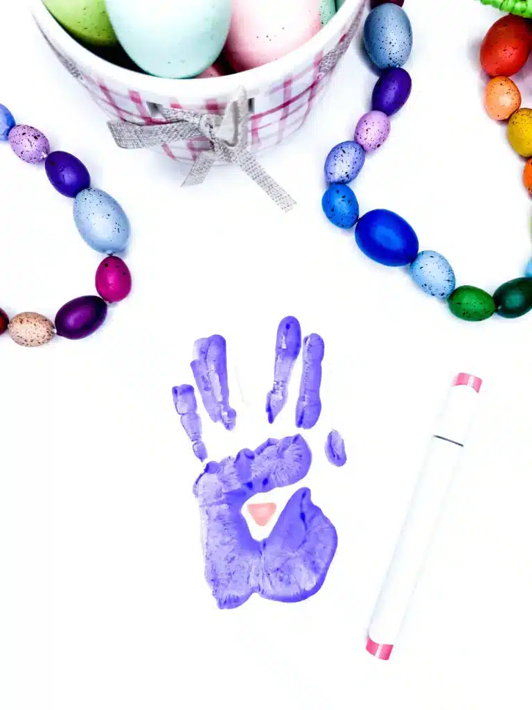Bunny Handprint Craft For Easter - Cultivating Brilliant Minds a purple handprint in paint with a pink bunny nose drawn on
