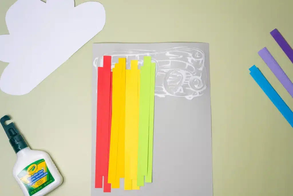 Rainbow Cloud Craft - Cultivating Brilliant Minds red, orange, yellow, and green strips of construction paper glued to a piece of paper